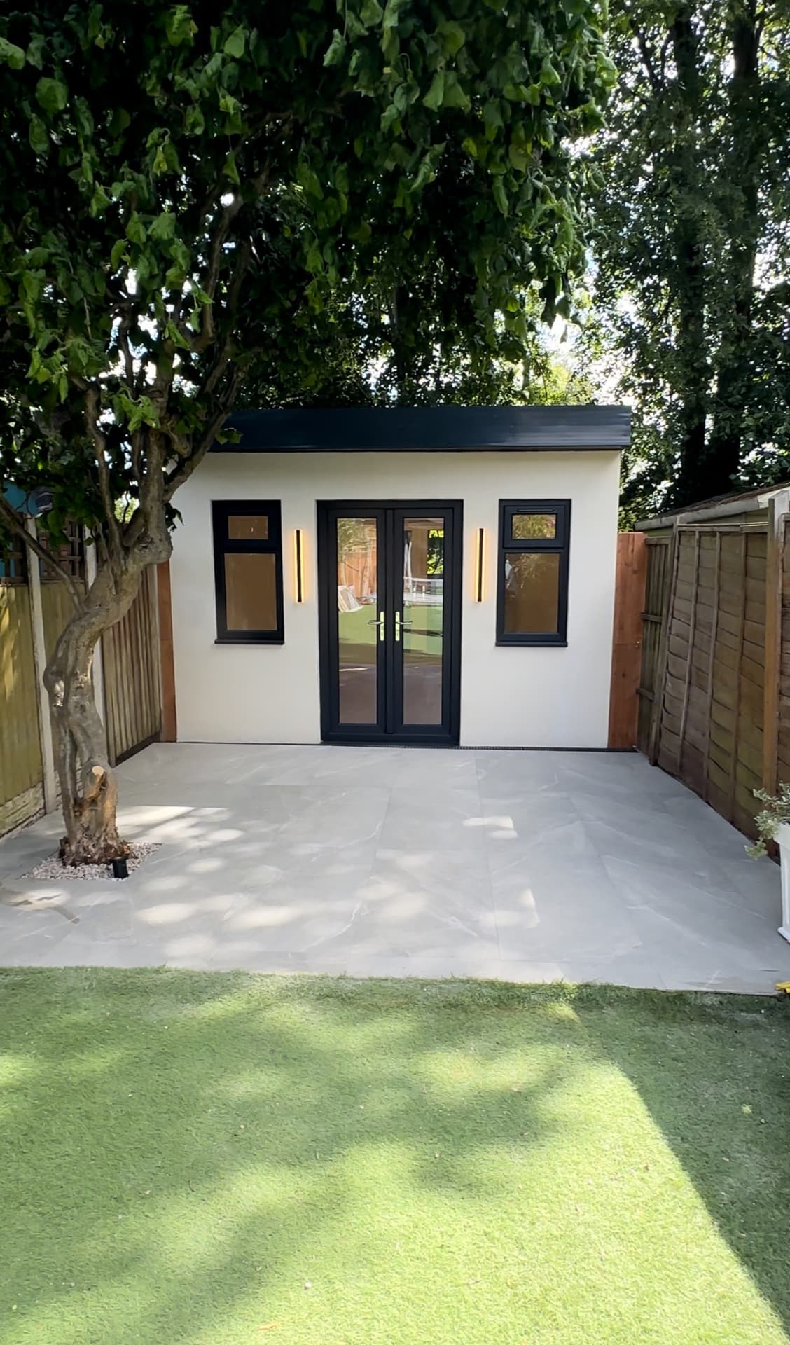 Finished garden room with black-framed doors and paved terrace