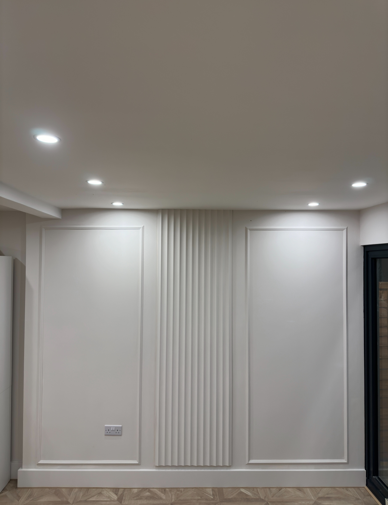Freshly renovated room with framed and fluted wall panelling and recessed downlights