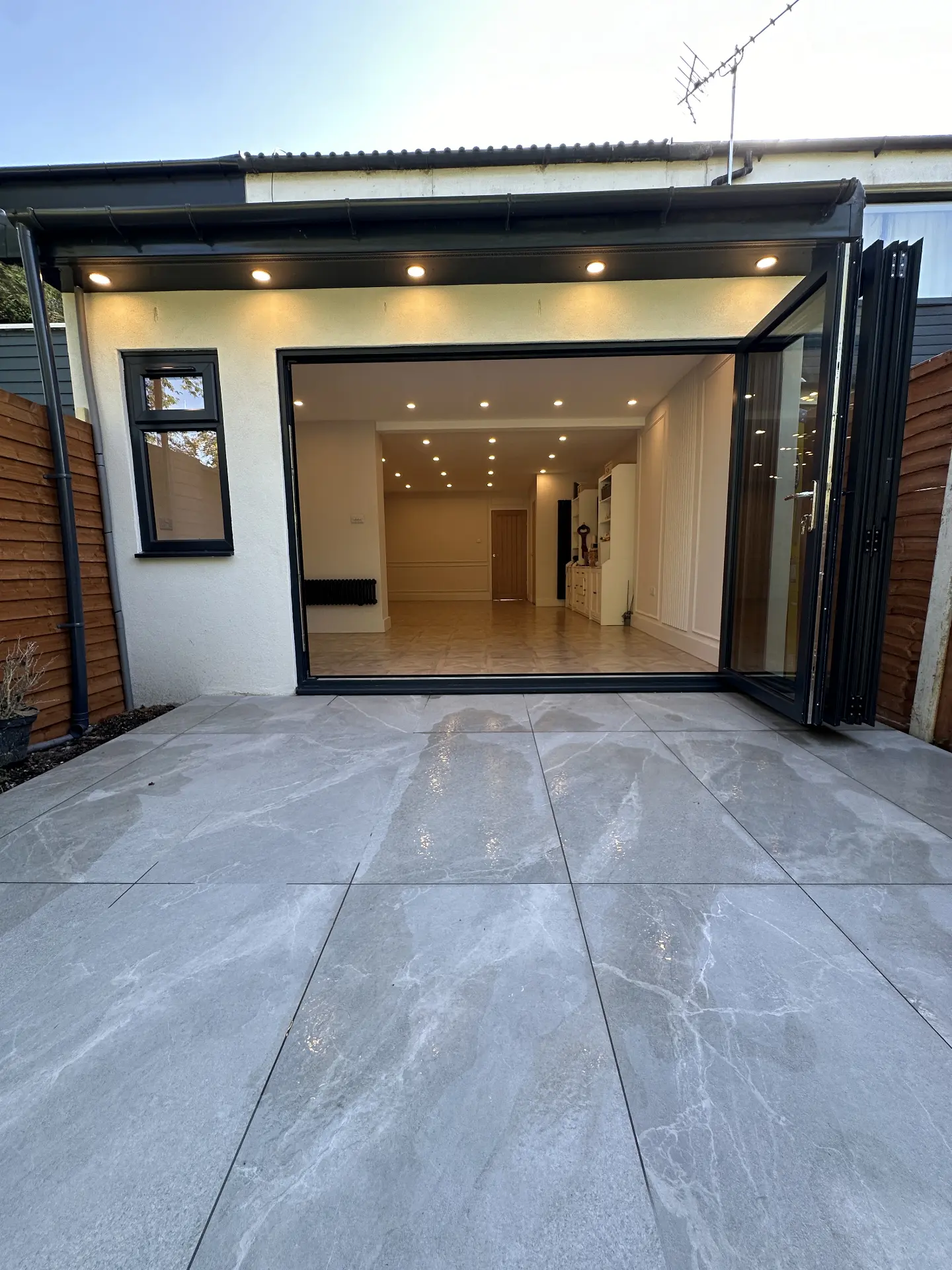 Rear extension with black bi-fold doors opening onto a porcelain patio