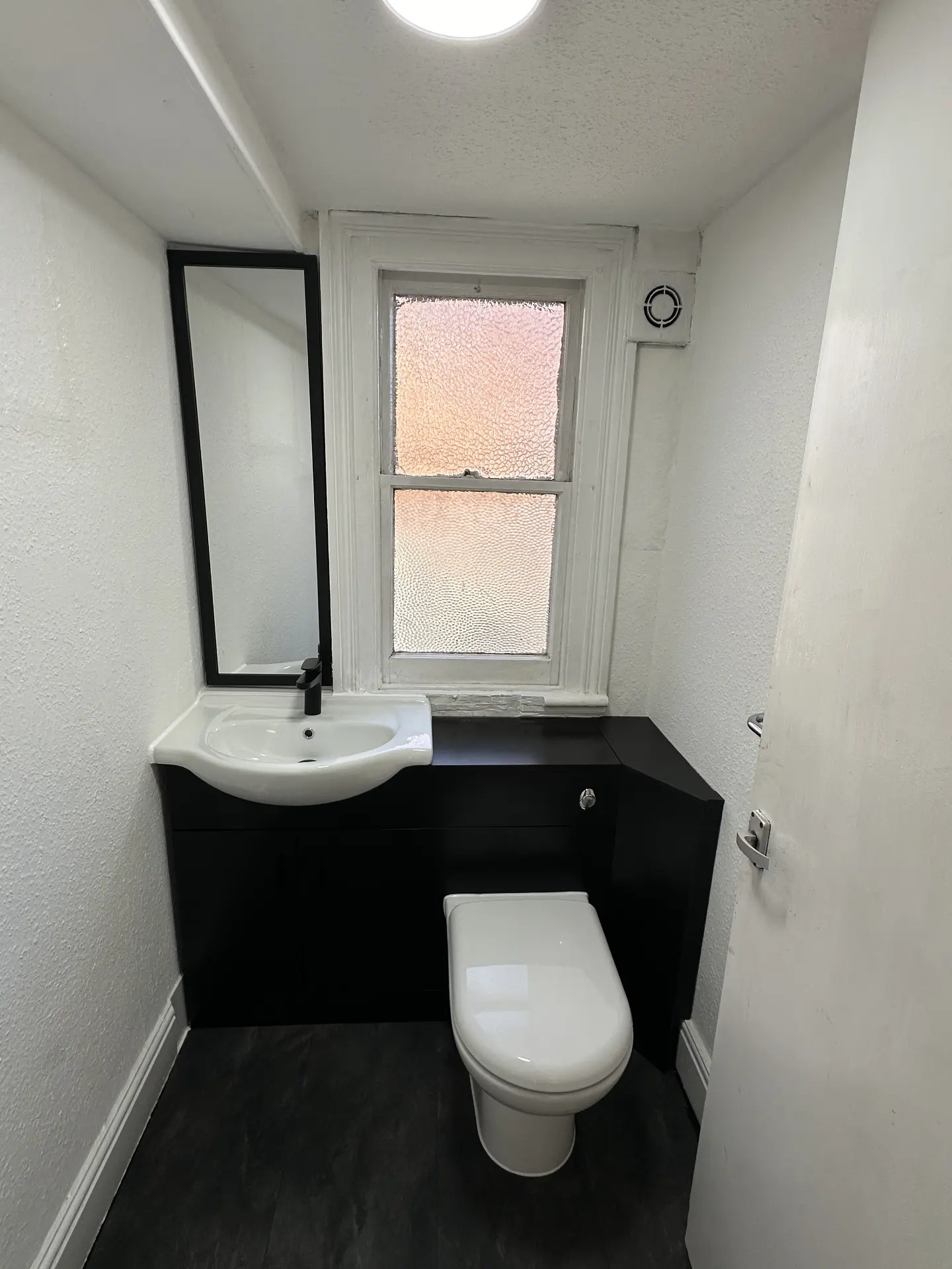Bespoke bathroom vanity and concealed toilet unit in a small cloakroom