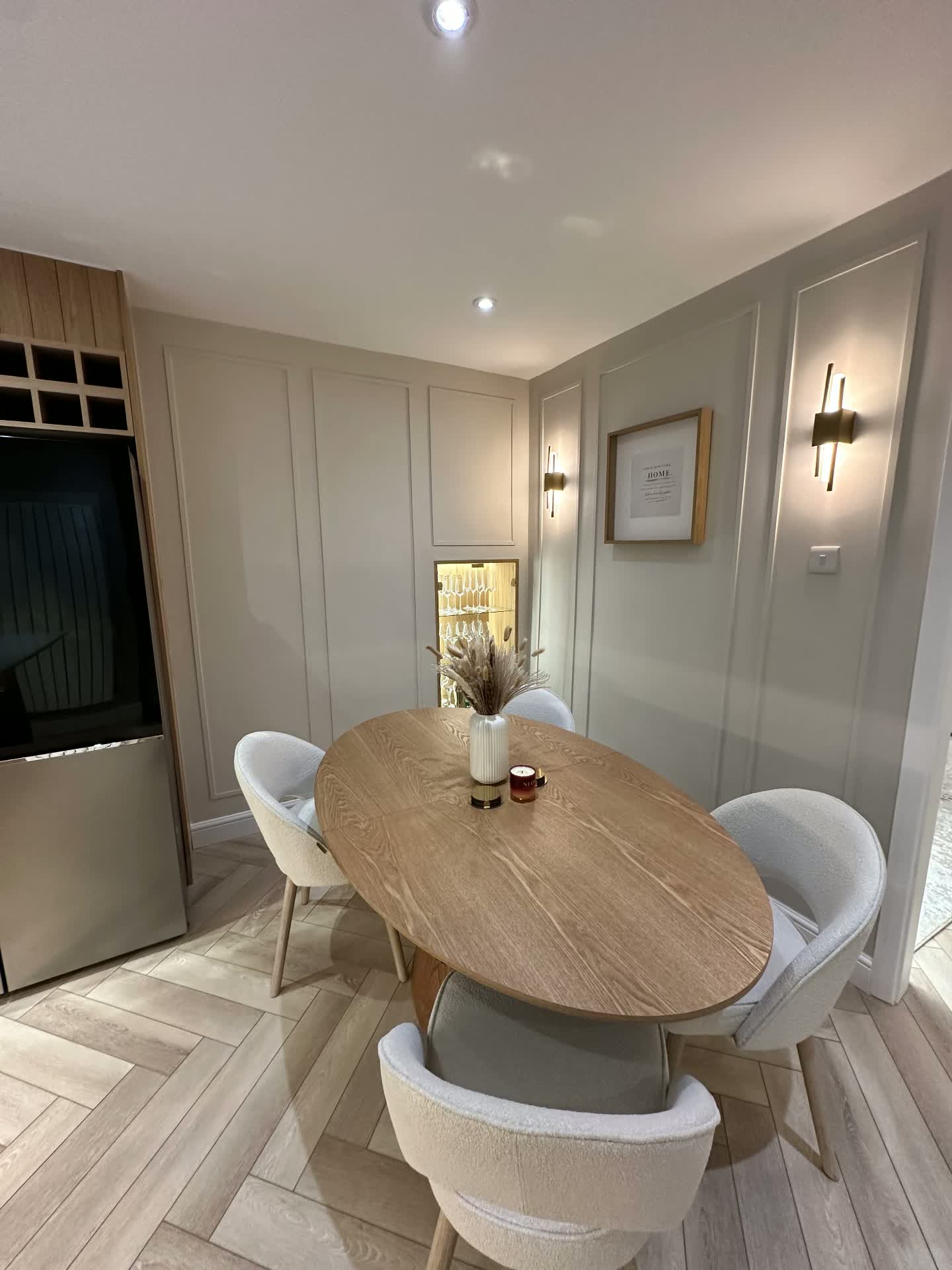 Dining area with wall panelling, brass wall lights and oval oak table