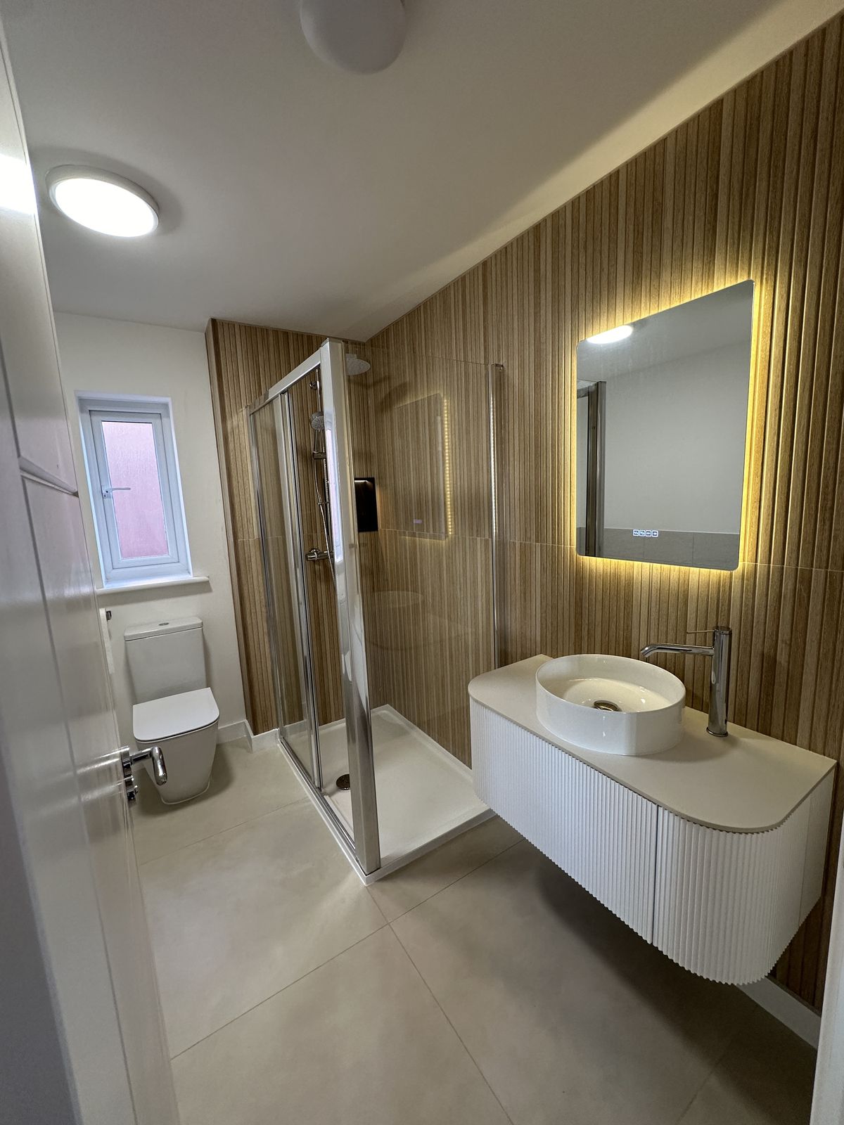 Bathroom with wood-slat wall and LED mirror
